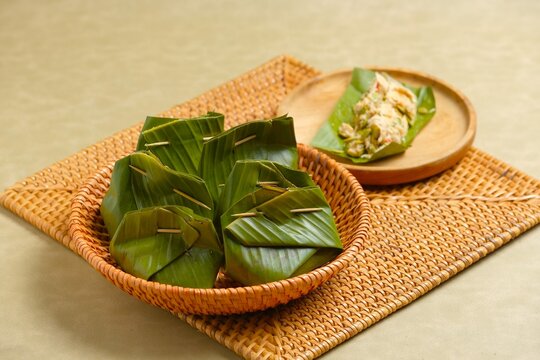 Bothok or bothok on brown background. Bothok is traditional Indonesian food. Made from tempeh, anchovy, chinese map and coconut grater wrap with banana leaf. Javanese food