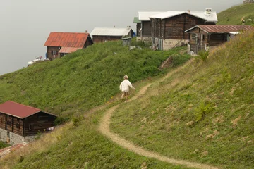 A little girl runs in the mountains against the backdrop of a village © Alex