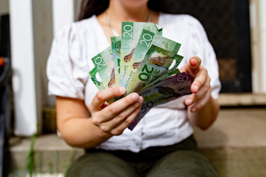 Close-up of a woman's hands holding New Zealand currency