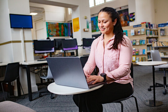 Maori woman studying and working with a laptop at a public library