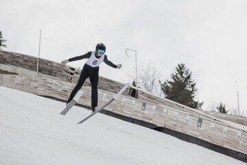 Obraz premium Athlete performing a ski jump during a training session on a ski jump hill, showcasing aerial technique and athletic skill.