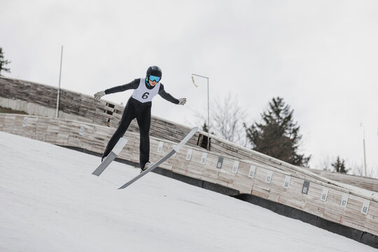 Athlete performing a ski jump during a training session on a ski jump hill, showcasing aerial technique and athletic skill.