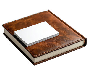 A stack of blank white business cards rests atop a textured brown leather-bound notebook against a black background.
