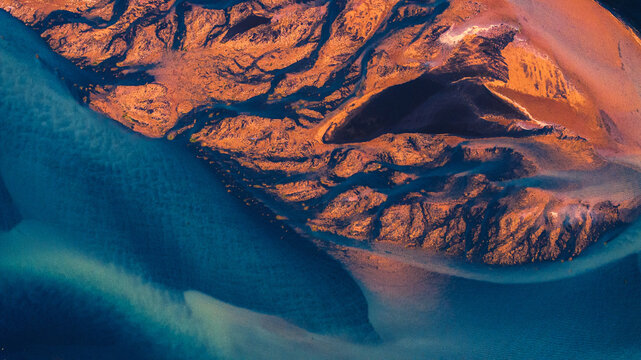 Aerial view of braided rivers carving through ochre earth, meeting the turquoise waters in a stunning display of nature's artistry, Selfoss, Southern Region, Iceland.