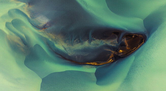 Aerial view of glacial rivers carve intricate patterns through the landscape, painting a surreal canvas of turquoise and gold, Selfoss, Southern Region, Iceland.