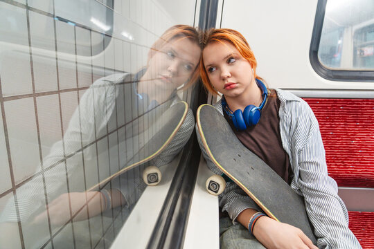 Sad skateboarder with headphones showing loneliness on metro