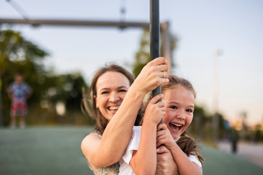 Mother and daughter smiling on zipline adventure outdoors at park