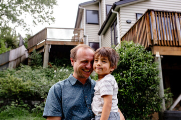 Smiling dad holding son in backyard