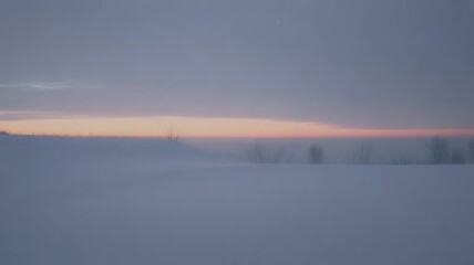 A low sun casts a pale orange glow above a vast, flat, snow-covered winter landscape under a muted sky.