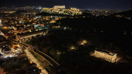 Naklejka premium Aerial drone night shot of amazing illuminated ancient market of Athens or Agora featuring temple of Hephaestus, picturesque Plaka district and Acropolis hill, Attica, Greece