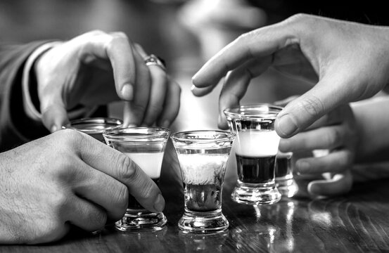 Shots on a bar counter top. Several alcohol shot glasses. Set of shot cocktails. Black and white