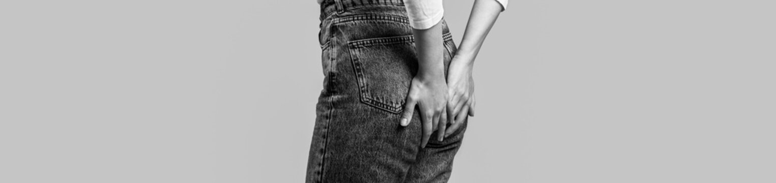 Woman holds his hands to the ass feeling pain. Pain, hemorrhoids. Black and white