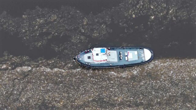 Top down aerial video of icebreaker tugboat at aqueduct in winter