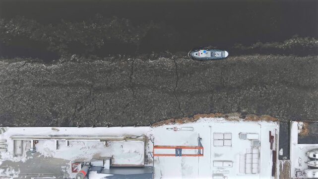 Top down aerial video of icebreaker tugboat at aqueduct in winter