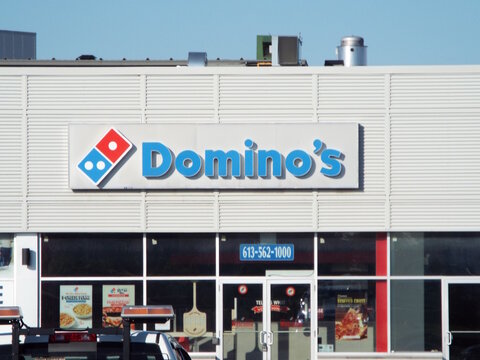 Ottawa, ON, Canada-July 8,2025: The "Domino's" Pizza storefront at 1010 Belfast Road features its iconic blue logo above glass windows and various promotional posters.