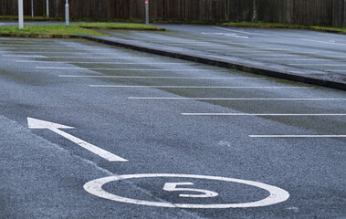 A large car park showing empty parking bays with white lines printed on tarmac. 