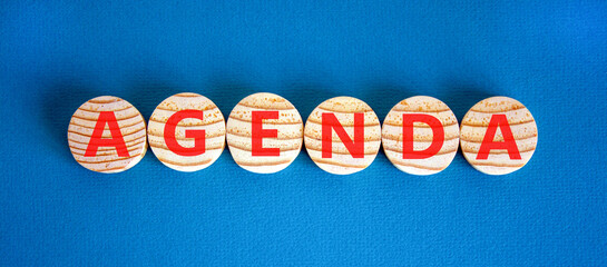 Agenda symbol. Concept word Agenda on beautiful wooden circles. Beautiful blue background. Business agenda concept. Copy space.