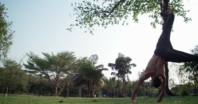 An athletic man performs a powerful round-off into a backflip in 1000fps slow motion. Captured at sunset, this parkour sequence highlights strength and explosive energy. Concept power, momentum, skill