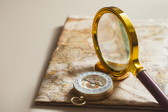 Compass examined through magnifying glass on vintage world map. Concept of travel navigation, strategic planning, business analysis, direction search, exploration and global positioning.