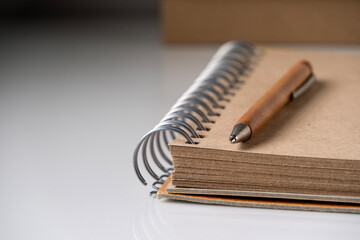 A wooden ballpoint pen lies on a notebook with craft sheets, close-up.