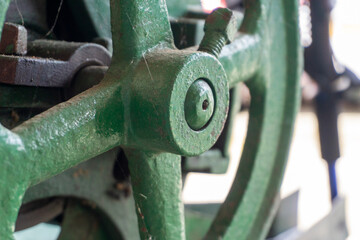 Vintage coffee pulping machine detail showing the green metal flywheel.