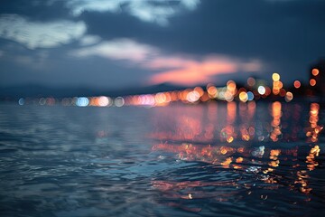 Blurry coastal lights reflect on rippling water at twilight