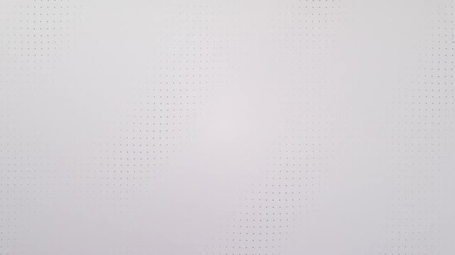 Abstract black dots slowly emerge on a clean white background