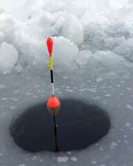 Ice fishing float in frozen lake during winter. © stepacarp23