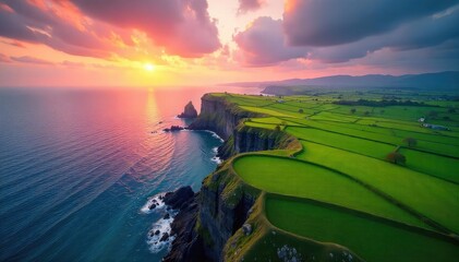 Stunning aerial shot of vibrant green fields meeting a dramatic, rocky coastline under a dramatic sunset sky Perfect for travel, nature, and environmental projects , color, drone