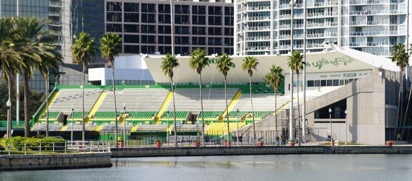 St Petersburg, Florida, U.S - Jan 2, 2026 - Al Lang Stadium, a historic waterfront sports stadium features green and yellow seating sections, lined with tall palm trees near urban high-rise buildings