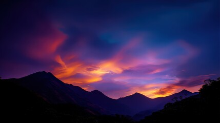 Vivid sunset colors illuminate dramatically silhouetted mountain range landscape