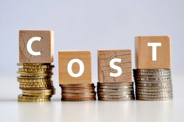 Wooden blocks with letters C O S T on stacks of gold and silver coins on white surface  business concept