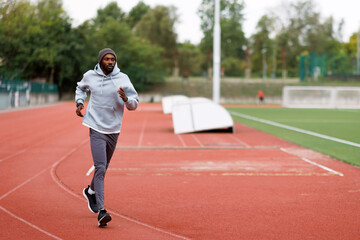 Black man running on athletic track outdoors