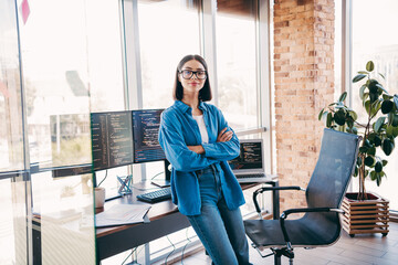 Professional woman programmer in modern loft office with multiple monitors and coding on screen
