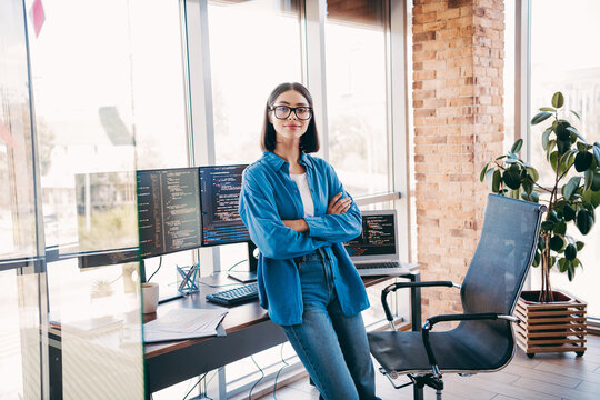 Professional woman programmer in modern loft office with multiple monitors and coding on screen