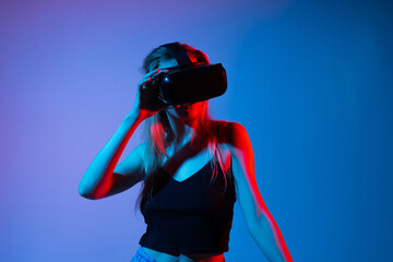 Woman touching virtual interface using VR headset, immersive virtual reality experience with futuristic blue and red neon lighting