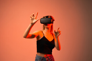 Woman wearing VR headset and using pinch gesture to select virtual elements in immersive digital environment with red studio lighting