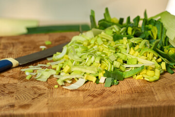 Chopped green onions are placed on a wooden cutting board