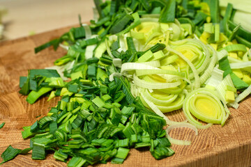 Chopped green onions are placed on a wooden cutting board