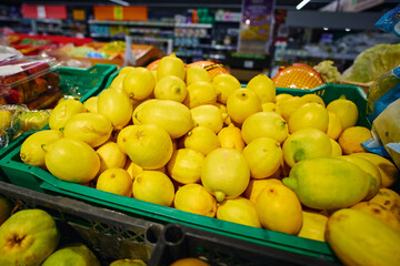 Lemons are piled high in a green basket at a grocery store