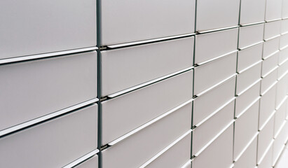 Obraz premium A close up view of a wall of metallic delivery lockers or parcel boxes, often used for contactless package pick up. The boxes are arranged in a neat, uniform grid, giving a clean and modern appearance