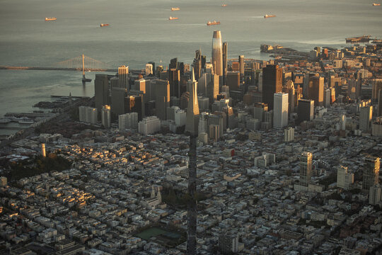 Aerial view of the towering Salesforce Tower piercing the sky, casting long shadows over the city grid as ships dot the bay, San Francisco, California, United States.
