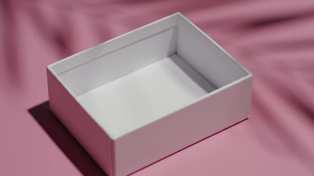 Minimalist white box on a pink background with soft shadows, perfect for product presentation.