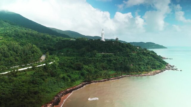 Lady buddha statue observing the vibrant green hills of son tra peninsula and the tranquil seascape, illustrating the cultural heritage and scenic beauty of da nang, vietnam