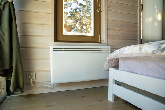 Electric convector heater warming modern wooden home interior, winter light. Concept energy efficient heating