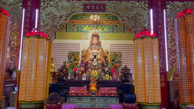 Ornate interior of Thean Hou Temple in Kuala Lumpur featuring a golden goddess statue, glowing prayer lamps, and Chinese religious decor. Language translation: Our Lady the day after tomorrow