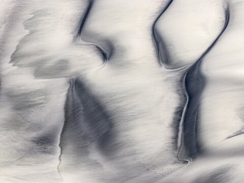 Aerial view of a mesmerizing landscape where stark white salt flats meet shadowy depths, creating an otherworldly canvas of textures and tones, White sands of El Penon, Puna Argentina.