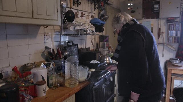 A woman prepares a meal in her cluttered kitchen. She moves around with utensils, checking pots and getting ingredients ready for cooking. The setting shows signs of daily life.