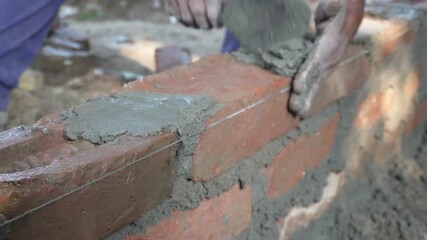 Person bricklaying bricks with mortar on construction site