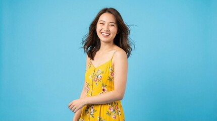 Happy Young Asian Woman in Yellow Floral Dress on Blue Background